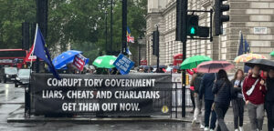 A banner outside Westminster station that reads "Corrupt Tory Government; Liars, Cheats and Charlatans; Get Them Out Now".